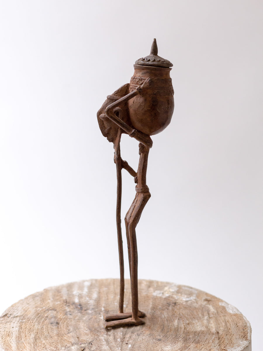Figura Dogón con Vasija - País: País Dogón, Mali Material: Aleación de bronce Medidas: 5x5x31cm